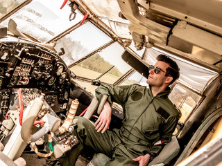 A handsome young pilot sitting in the cockpit - obrazy, fototapety, plakaty