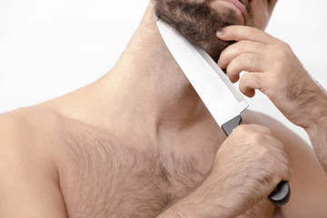 Man shaving his beard with a knife