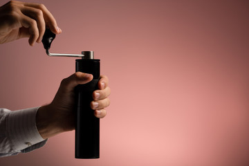 A man grinds grain coffee with a manual coffee grinder