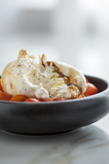 Burrata Büffelmozzarella Kugel mit Tomaten, Olivenöl und Balsamico auf schwarzen Teller