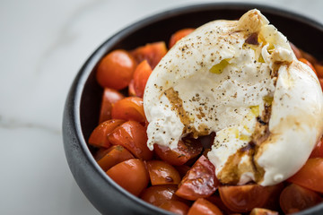 Burrata Büffelmozzarella Kugel mit Tomaten, Olivenöl und Balsamico auf schwarzen Teller