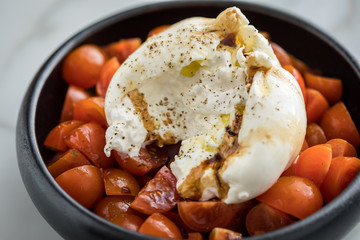 Burrata Büffelmozzarella Kugel mit Tomaten, Olivenöl und Balsamico auf schwarzen Teller