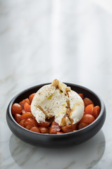 Burrata Büffelmozzarella Kugel mit Tomaten, Olivenöl und Balsamico auf schwarzen Teller
