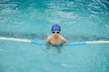 Fototapeta na wymiar top view of a 7-year boy playing and swimming in the swimming pool