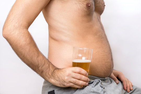Man with a fat belly holds a glass of beer