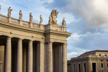 Obraz premium Roof of Saint Peter's Cathedral in the Vatican with various statues and sculptures on it, columns below and cathedral's dome above and on the right. Vatican, Rome, Italy