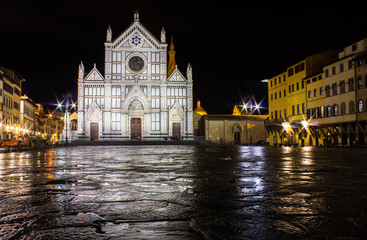 Fototapeta na wymiar Night photo, illuminated cathedral Santa Croce, wet after rain ground of square (piazza) reflecting church facade and nearby residential buildings. Long exposure photography.