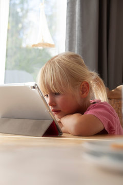 Portrait of blond little girl using digital tablet at home