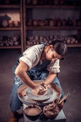 Stylish craftsman demonstrates the process of making ceramic dishes using the old technology. Folk...