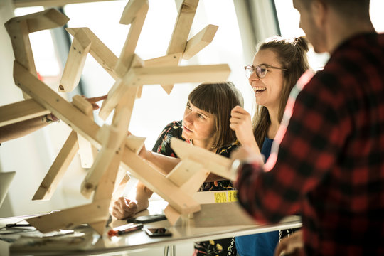 Group of creative professionals building wood object for a project
