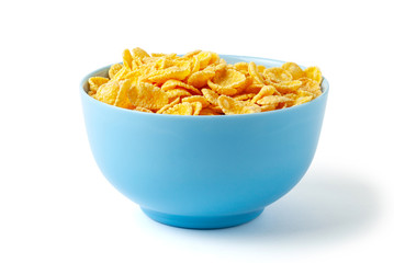 Dry breakfast cornflakes. Blue plate full of cereal. Isolated on white background.