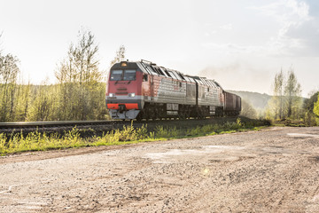 Freight train hauled by the diesel locomotives passing the forest