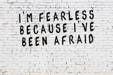 White brick wall with painted black motivational quote inscription