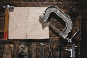 To do list mock up. Construction handbook with blank pages and old construction tools on a wooden workbench flat lay background. Carpentry. Woodwork.