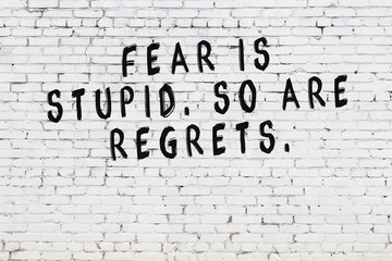 White brick wall with painted black motivational quote inscription