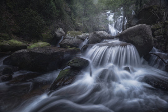 Landscape of beautiful waterfall flow in long exposure on heavy boulders in wild woods