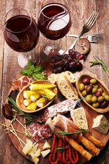 antipasto various appetizer. Cutting board with prosciutto, salami, cheese, bread and olives on dark wooden background