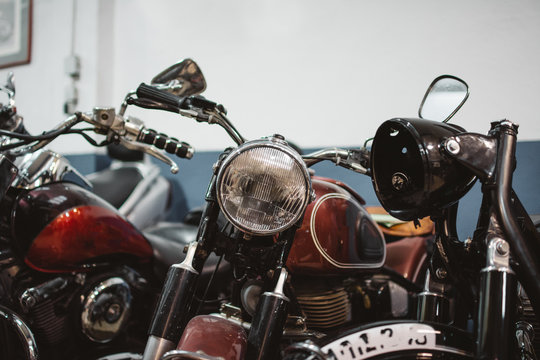 Shabby vintage motorbikes with broken headlights parked inside repair workshop