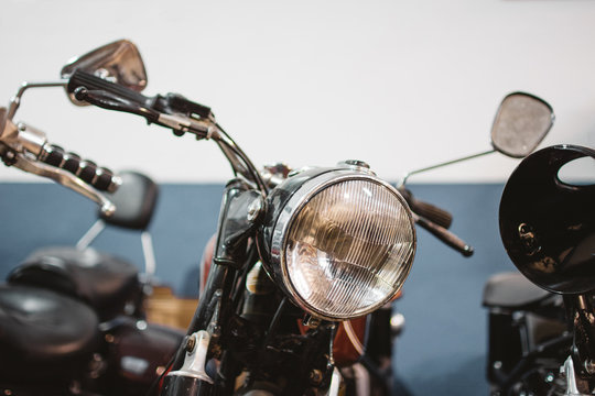 Shabby vintage motorbikes with broken headlights parked inside repair workshop