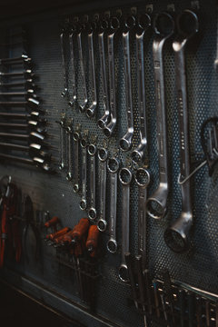 Set of assorted repair tools attached to grungy metal wall in professional workshop
