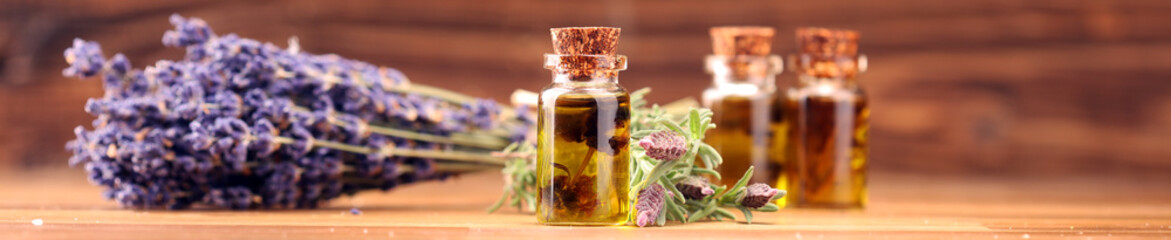 essential lavender oil in a glass bottle on a background of fresh flowers - obrazy, fototapety, plakaty