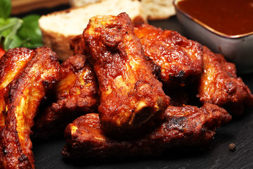 Spicy hot grilled spare ribs from a summer BBQ served with fresh tomatoes on an vintage cutting board