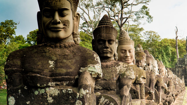 Ancient stone statues of Buddha placed in row on terrace of temple, Cambodia