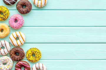 Fototapeta na wymiar Modern design with bright donuts on mint green wooden background top view mock up