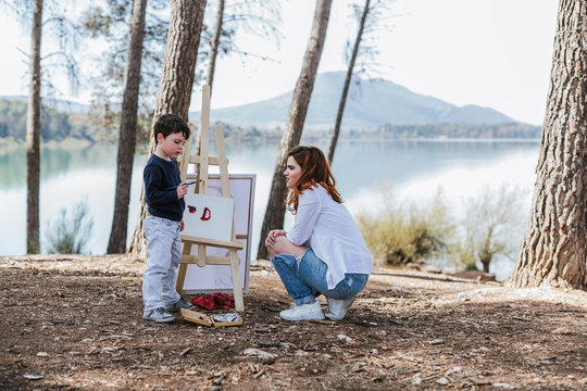 Mother and boy painting near lake