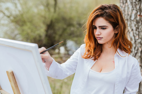 Young woman painting in countryside