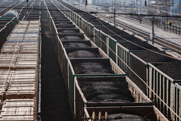 A lot of cars are on the railroad tracks. Freight trains. Freight shipping. Coal, wood planks, gravel, crushed stone. Wagons. Railway carriage.