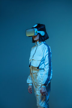 Excited young woman having virtual reality experience in neon light