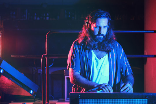 Bearded Dj man playing disco music in a club