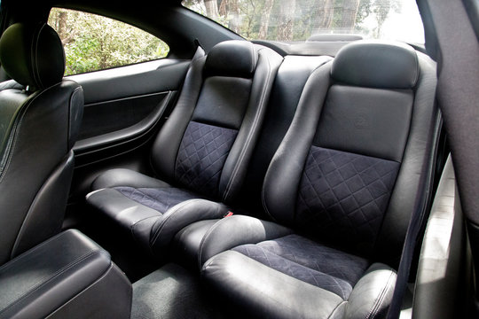 Bucket Seats In The Back Of A Fast Red Sports Car. Made Of Black And Dark Grey Or Charcoal Fabric And Leather. Designed For Comfort And Safety. Modern, Stylish Car Interior.