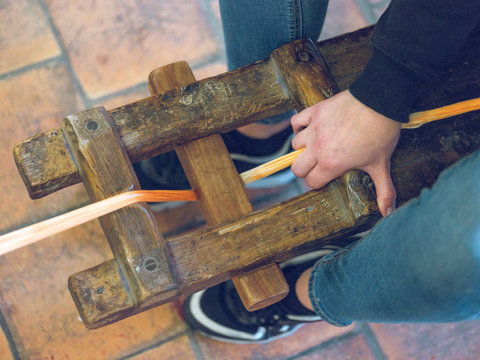 Unrecognizable person using old wooden frame to spin thread over tiled floor
