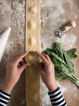 Bunch of ripe sorrel and various utensils placed over flour near uncooked raviolis and dough on kitchen table
