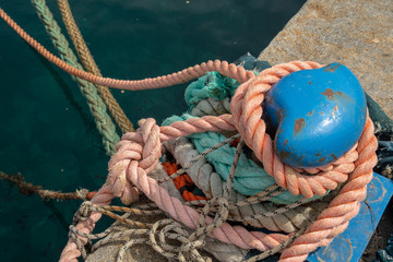 Fototapeta premium Close-up of a blue metal bollard with knotted nautical ropes on a pier of an harbor, Sestri Levante, Liguria, Italy