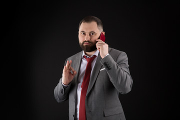 Naklejka premium Guy call friend stand black background. Mobile call concept. Man formal suit call someone. Mobile call conversation. Mobile negotiations. Businessman well groomed mature man hold smartphone.