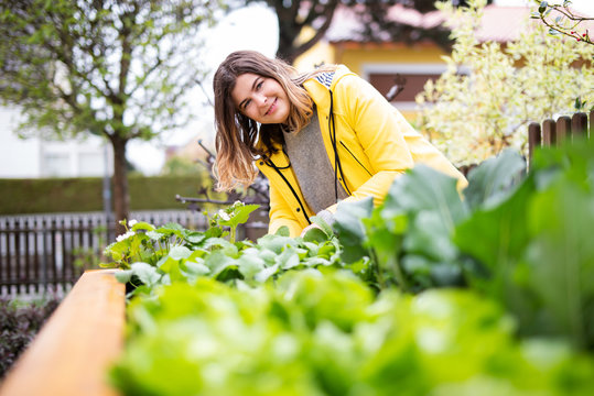 Junge Frau bei der Gartenarbeit an einem Hochbeet 