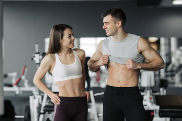Fototapeta na wymiar Sporty fitness couple showing in gym. Beautiful athletic man and woman, muscular torso abs.