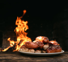 Hot sausages on a burning fire background on the kitchen table.
