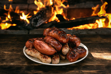 Hot sausages on a burning fire background on the kitchen table.