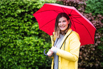 Mit Regenschirm und Regenjacke draußen im Regen 