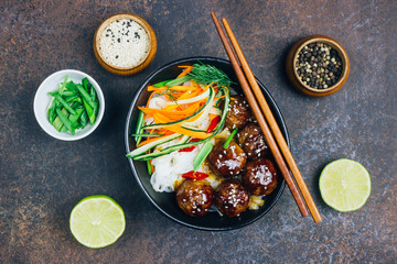Meatballs with teriyaki souce, rice noodle, vegetables and sesame seeds