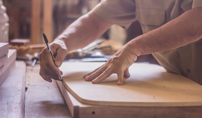 carpenter cutting plank with saw