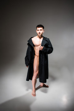 Naked Attractive Sexy Young Man Wearing Black Coat Posing In Photo Studio