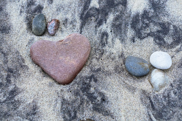 sea stone in the shape of a heart on the sand, red stone heart