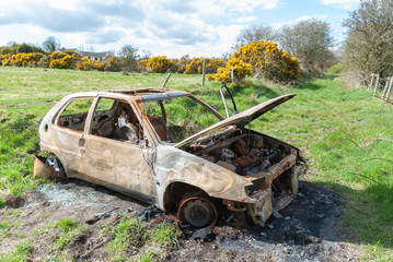 Burned out car in a country lane.