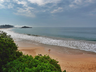 Surfer on beach in Mirissa. View from the Paradise Beach Club Hotel. Sri Lanka, March 16, 2019 © Jana Kollarova
