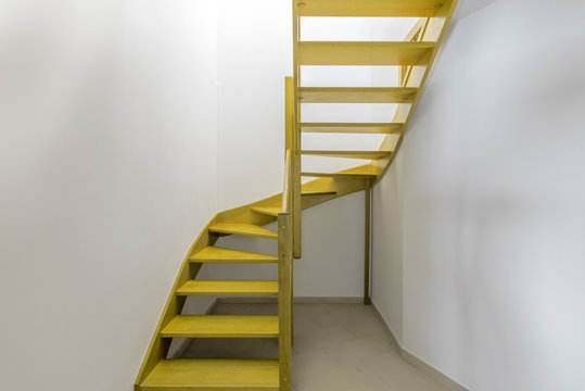 Escalera de ida y vuelta  amarilla delante de pared blanca.